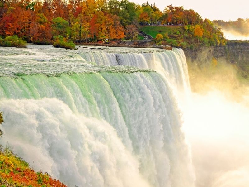 green and white waterfalls with yellow and red and orange trees